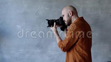 年轻英俊的摄影师留着胡子，在摄影棚里用专业的相机拍照。 <strong>后台后台</strong>